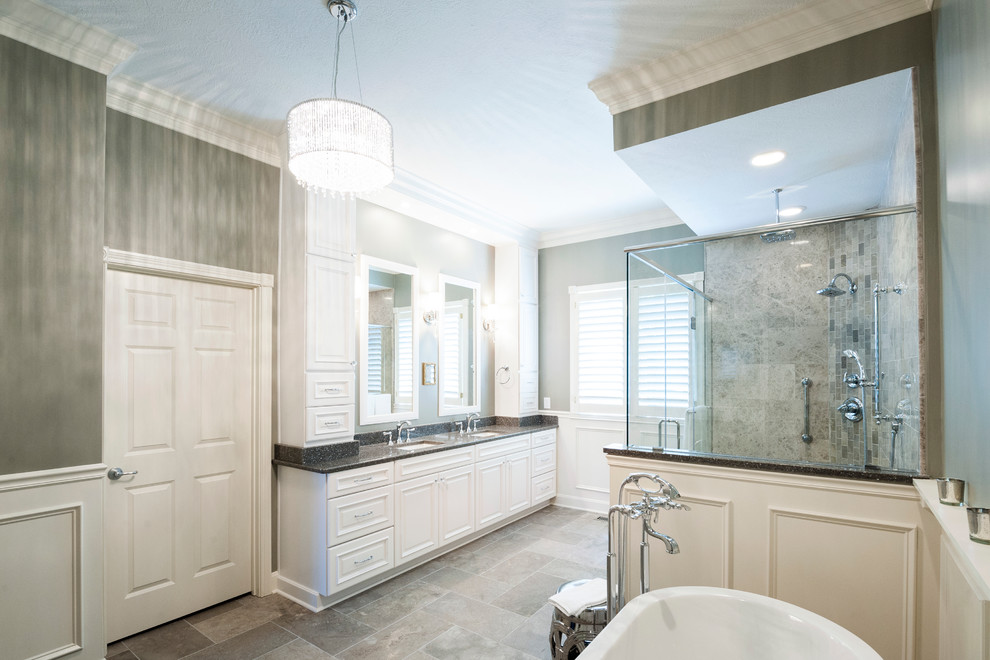 Photo of an expansive transitional master bathroom in Indianapolis with an undermount sink, furniture-like cabinets, white cabinets, quartzite benchtops, a freestanding tub, a corner shower, a two-piece toilet, gray tile, stone tile, grey walls and marble floors.
