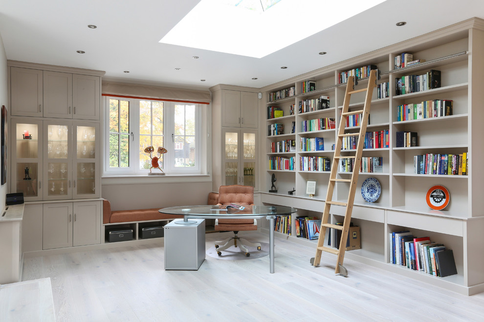 Design ideas for a transitional home office in London with a library, a freestanding desk and beige floor.