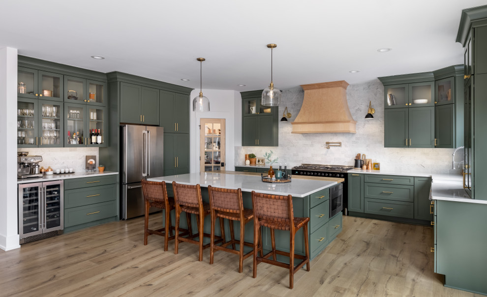 Design ideas for a large traditional u-shaped open plan kitchen in Detroit with a farmhouse sink, shaker cabinets, green cabinets, quartz benchtops, white splashback, marble splashback, stainless steel appliances, light hardwood floors, with island, beige floor and white benchtop.