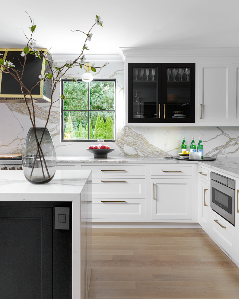 Large elegant u-shaped medium tone wood floor and brown floor enclosed kitchen photo in New York with an undermount sink, recessed-panel cabinets, white cabinets, marble countertops, multicolored backsplash, marble backsplash, paneled appliances, an island and multicolored countertops