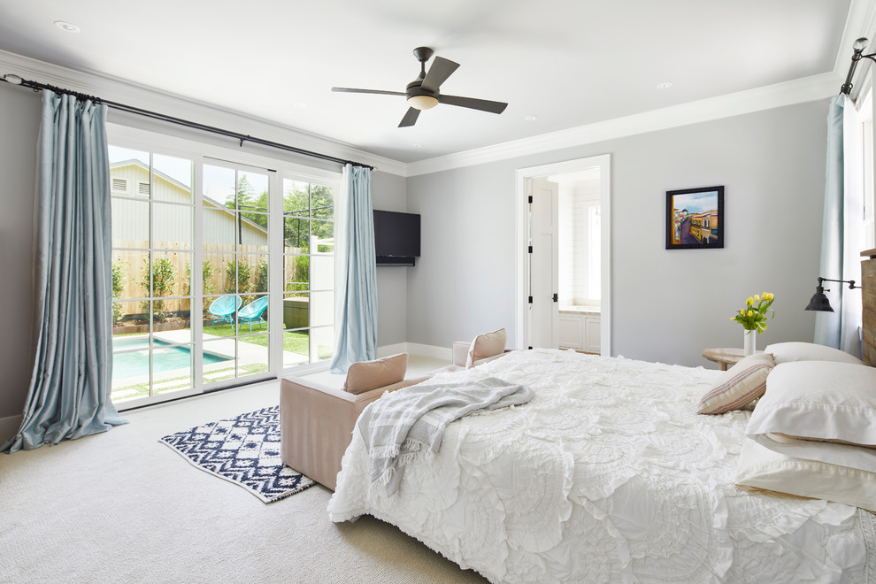 Large country master bedroom in Austin with white walls, carpet and beige floor.