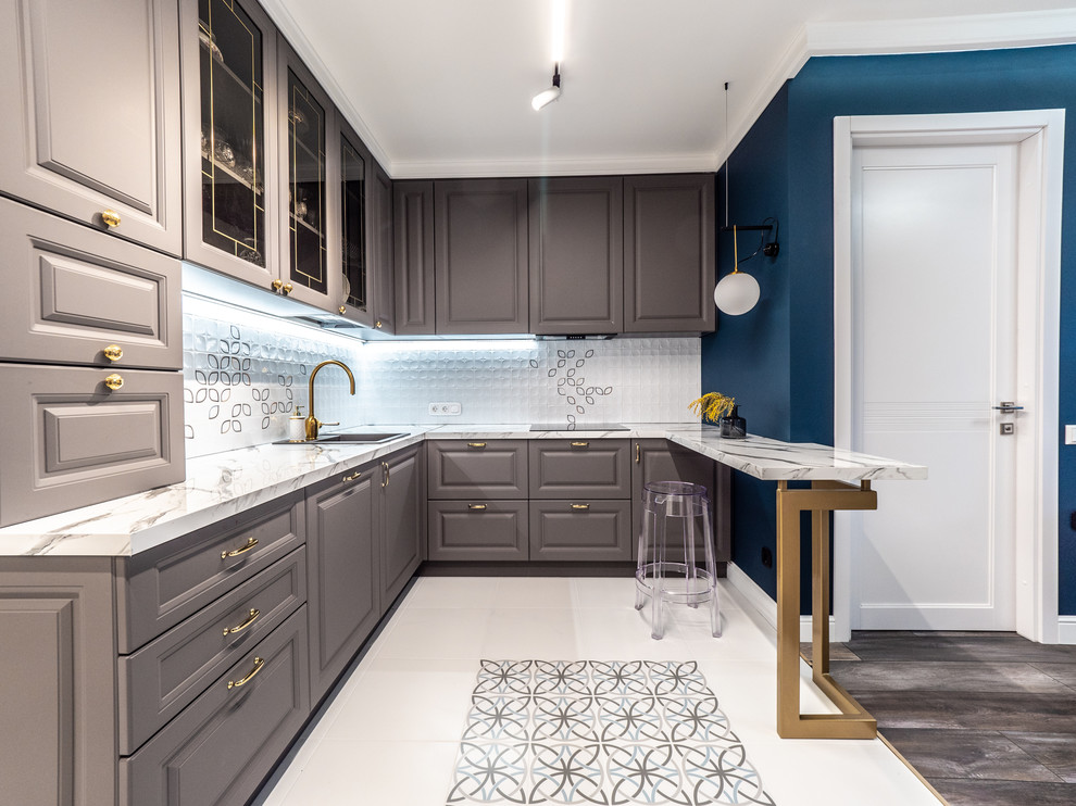 Small transitional u-shaped open plan kitchen in Saint Petersburg with grey cabinets, marble benchtops, white splashback, ceramic splashback, panelled appliances, porcelain floors, a peninsula, white floor, white benchtop, a drop-in sink and raised-panel cabinets.