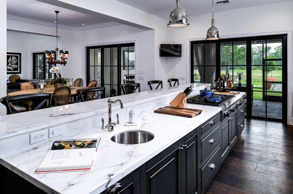 This is an example of a large transitional l-shaped eat-in kitchen in Miami with a farmhouse sink, recessed-panel cabinets, black cabinets, marble benchtops, multi-coloured splashback, stone slab splashback, stainless steel appliances, dark hardwood floors and with island.