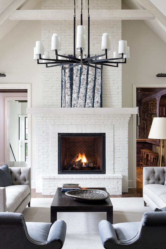 This is an example of a large traditional open concept living room in Minneapolis with white walls, a standard fireplace, a brick fireplace surround, brown floor and medium hardwood floors.