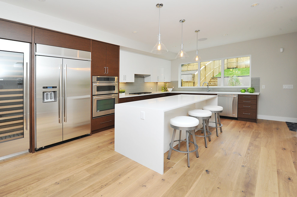 Large transitional l-shaped medium tone wood floor eat-in kitchen photo in Calgary with an undermount sink, flat-panel cabinets, medium tone wood cabinets, gray backsplash, stainless steel appliances and an island