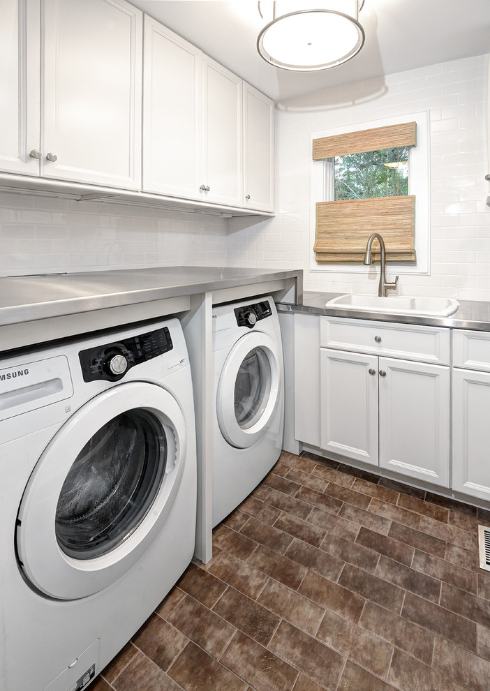 This is an example of a small transitional l-shaped dedicated laundry room in Charleston with white cabinets, stainless steel benchtops, white walls, ceramic floors, a side-by-side washer and dryer, recessed-panel cabinets and a drop-in sink.
