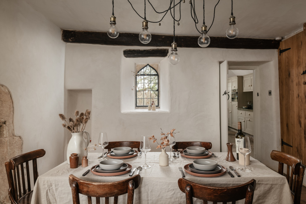 Design ideas for a mid-sized country separate dining room in Gloucestershire with beige walls, painted wood floors, no fireplace, brown floor, exposed beam and brick walls.