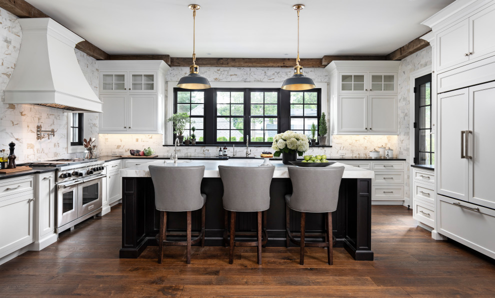 Inspiration for a large farmhouse u-shaped medium tone wood floor and brown floor kitchen remodel in Detroit with an undermount sink, shaker cabinets, white cabinets, beige backsplash, paneled appliances, an island and black countertops