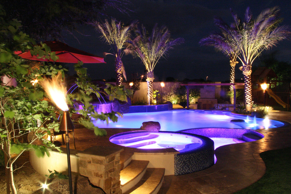 Large mediterranean backyard custom-shaped natural pool in Phoenix with natural stone pavers.