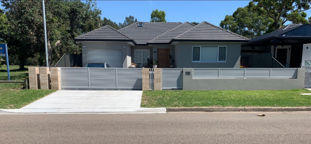 This is an example of a medium sized and gey contemporary bungalow render detached house in Sydney with a hip roof, a tiled roof and a grey roof.