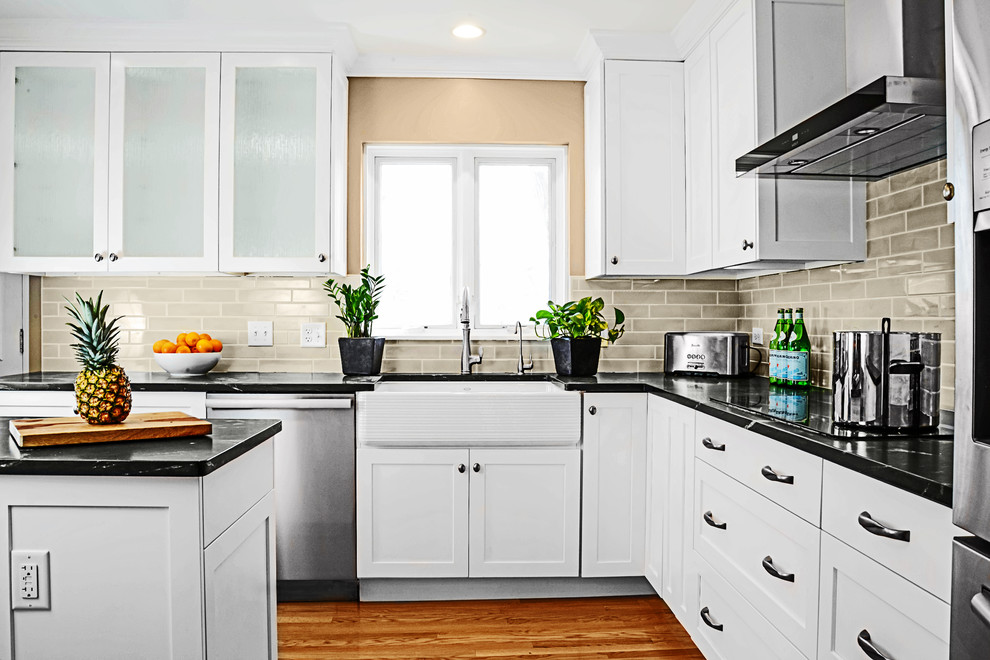 Example of a mid-sized transitional u-shaped medium tone wood floor eat-in kitchen design with a farmhouse sink, shaker cabinets, white cabinets, onyx countertops, gray backsplash, subway tile backsplash, stainless steel appliances and an island