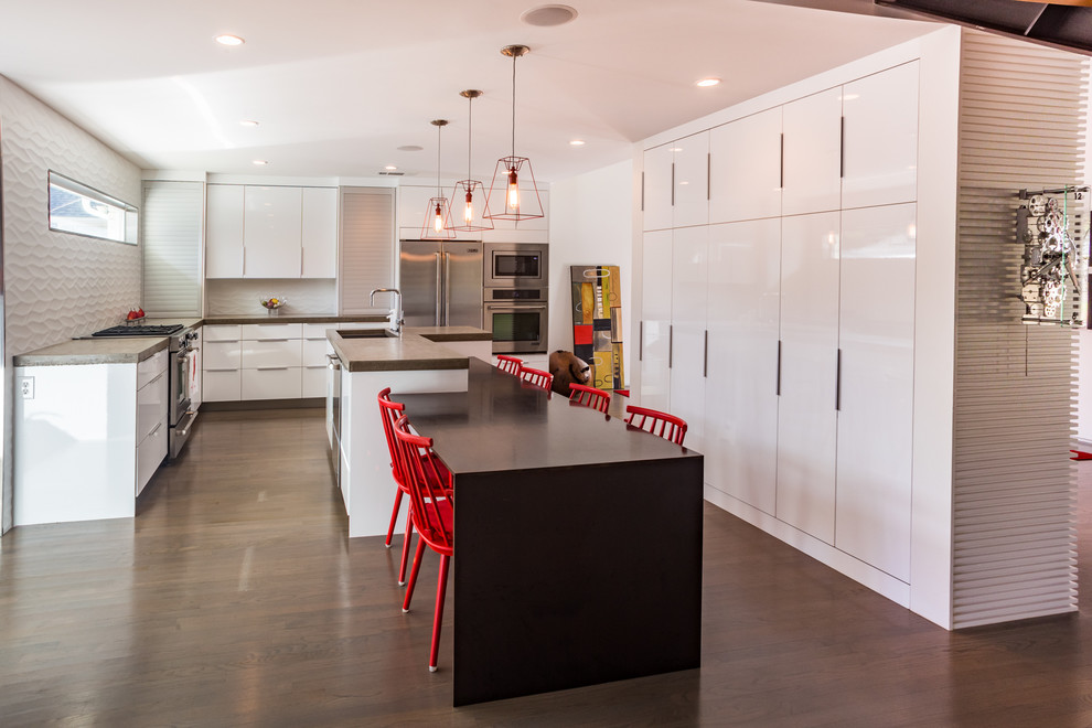This is an example of a modern kitchen in Dallas with an undermount sink, flat-panel cabinets, white cabinets, concrete benchtops, white splashback, porcelain splashback, stainless steel appliances and light hardwood floors.