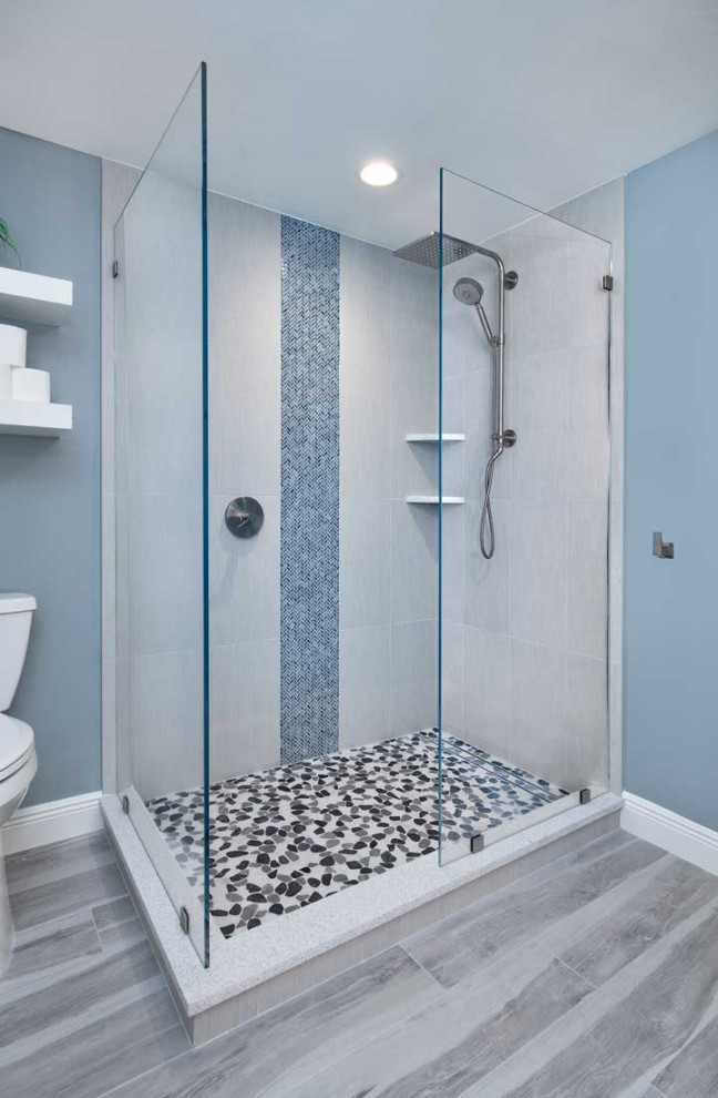 Cette image montre une grande salle de bain principale design avec un placard avec porte à panneau surélevé, des portes de placard bleues, une douche d'angle, WC séparés, un carrelage gris, des carreaux de céramique, un mur gris, un sol en carrelage de céramique, un lavabo encastré, un plan de toilette en quartz modifié, un sol gris, aucune cabine, un plan de toilette blanc, meuble double vasque et meuble-lavabo suspendu.