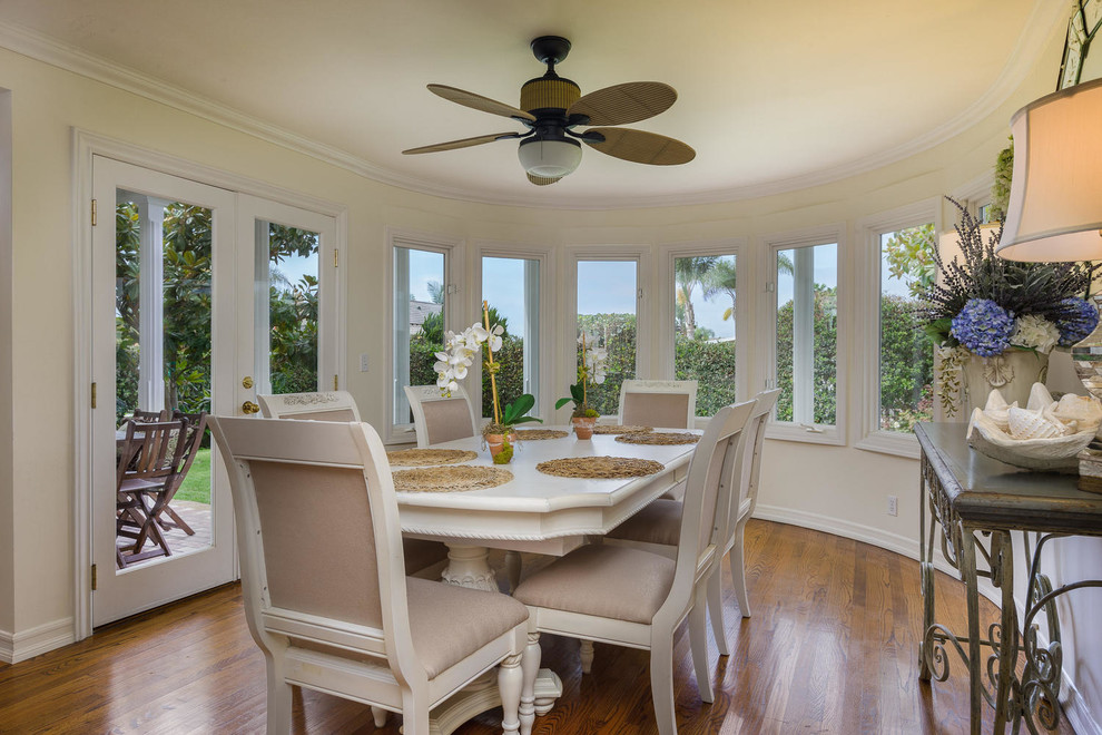 This is an example of a beach style dining room in San Diego with beige walls and dark hardwood floors.