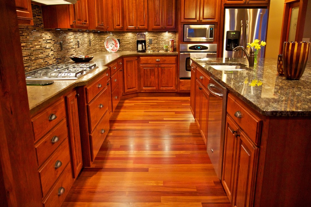 Inspiration for a large l-shaped medium tone wood floor open concept kitchen remodel with an undermount sink, raised-panel cabinets, dark wood cabinets, multicolored backsplash, glass tile backsplash, stainless steel appliances and an island