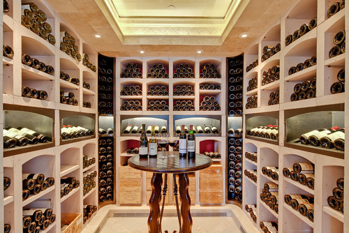 A large wine cellar featuring a round wood pub table in the center with wine glasses