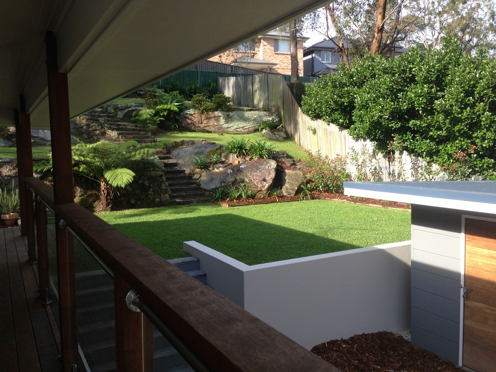 Photo of a large modern sloped partial sun formal garden for spring in Sydney with natural stone pavers.