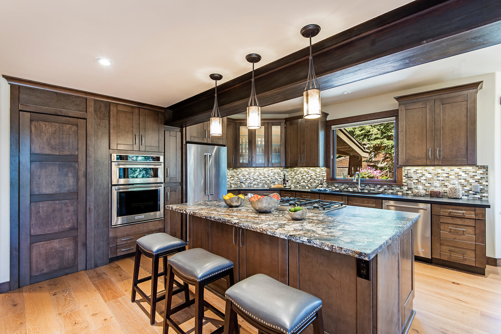 Large mountain style l-shaped light wood floor eat-in kitchen photo with an undermount sink, shaker cabinets, medium tone wood cabinets, granite countertops, gray backsplash, subway tile backsplash, stainless steel appliances and an island