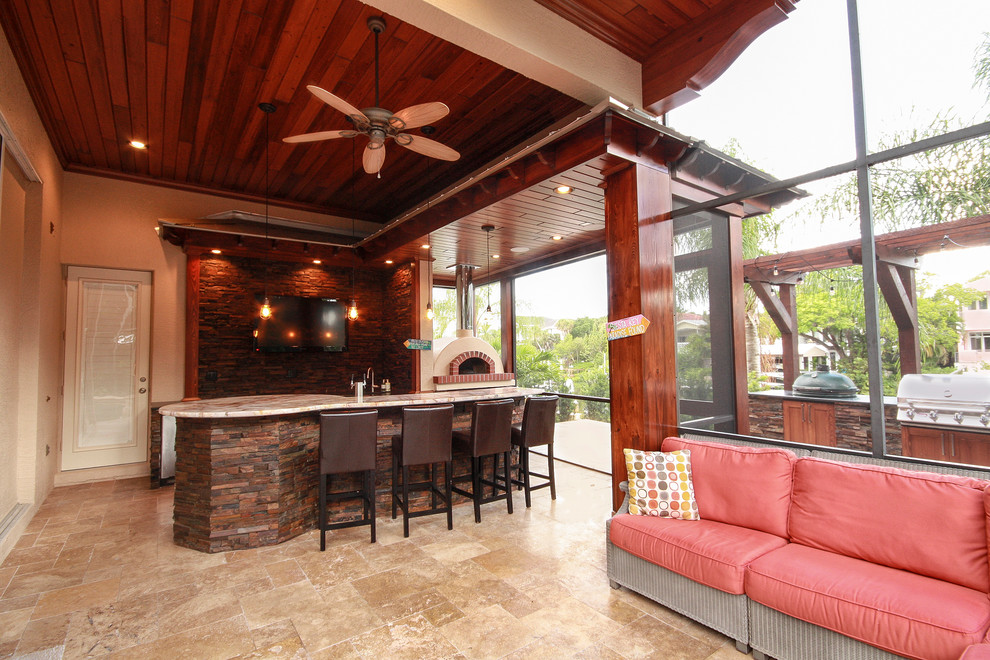 This is an example of an expansive transitional backyard patio in Tampa with an outdoor kitchen, natural stone pavers and a roof extension.
