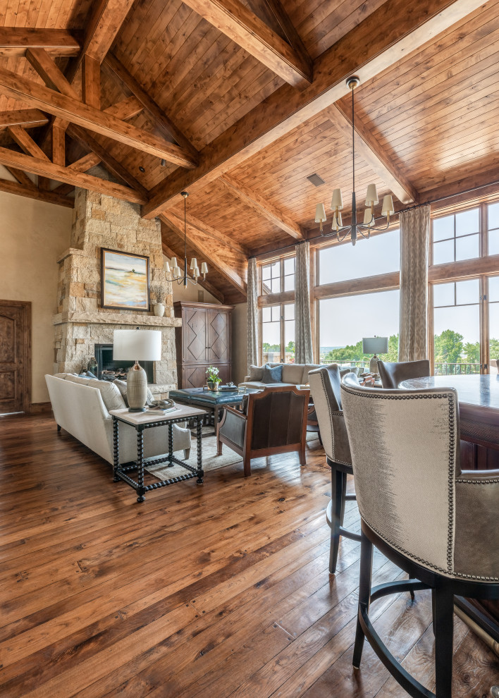 Inspiration for an expansive traditional open concept living room in Denver with beige walls, medium hardwood floors, a standard fireplace, a stone fireplace surround, a concealed tv and vaulted.