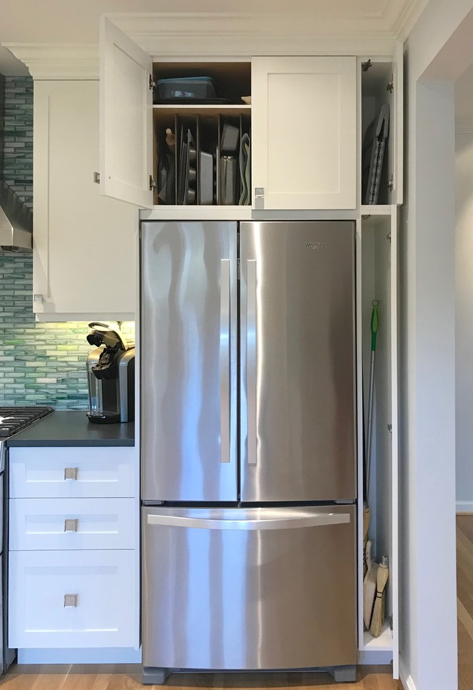 Small arts and crafts l-shaped eat-in kitchen in Seattle with an undermount sink, shaker cabinets, white cabinets, solid surface benchtops, blue splashback, glass tile splashback, stainless steel appliances, light hardwood floors, yellow floor and grey benchtop.