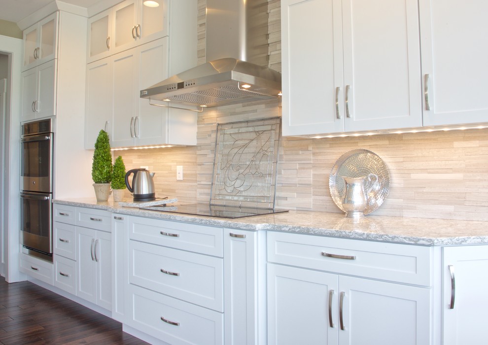 Example of a mid-sized transitional galley eat-in kitchen design with white cabinets, granite countertops, beige backsplash, stone tile backsplash and stainless steel appliances
