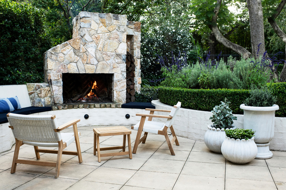 This is an example of a small traditional courtyard patio in Sydney with with fireplace and natural stone pavers.