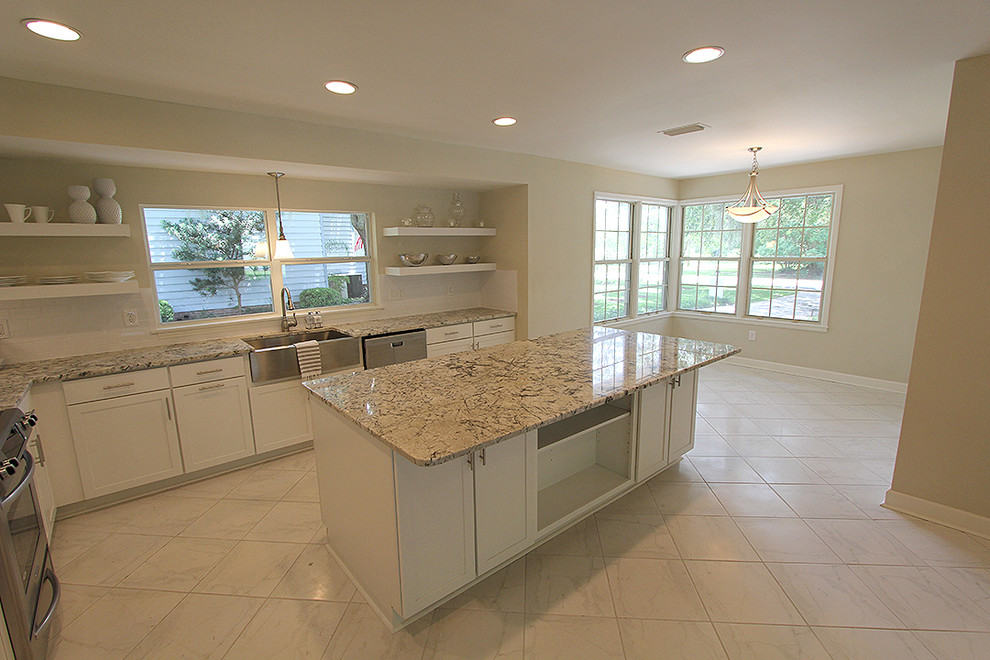 Example of a large transitional l-shaped white floor eat-in kitchen design in Jacksonville with a farmhouse sink, shaker cabinets, white cabinets, granite countertops, white backsplash, subway tile backsplash, stainless steel appliances and an island