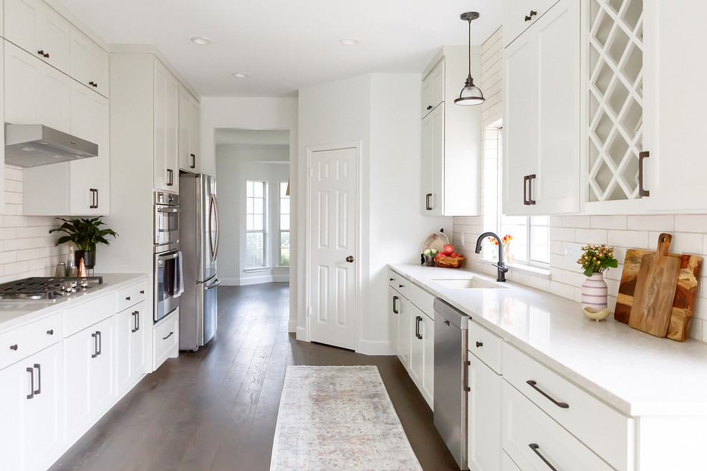 Mid-sized transitional galley medium tone wood floor and brown floor enclosed kitchen photo in Austin with an undermount sink, shaker cabinets, gray cabinets, quartz countertops, beige backsplash, porcelain backsplash, stainless steel appliances and gray countertops