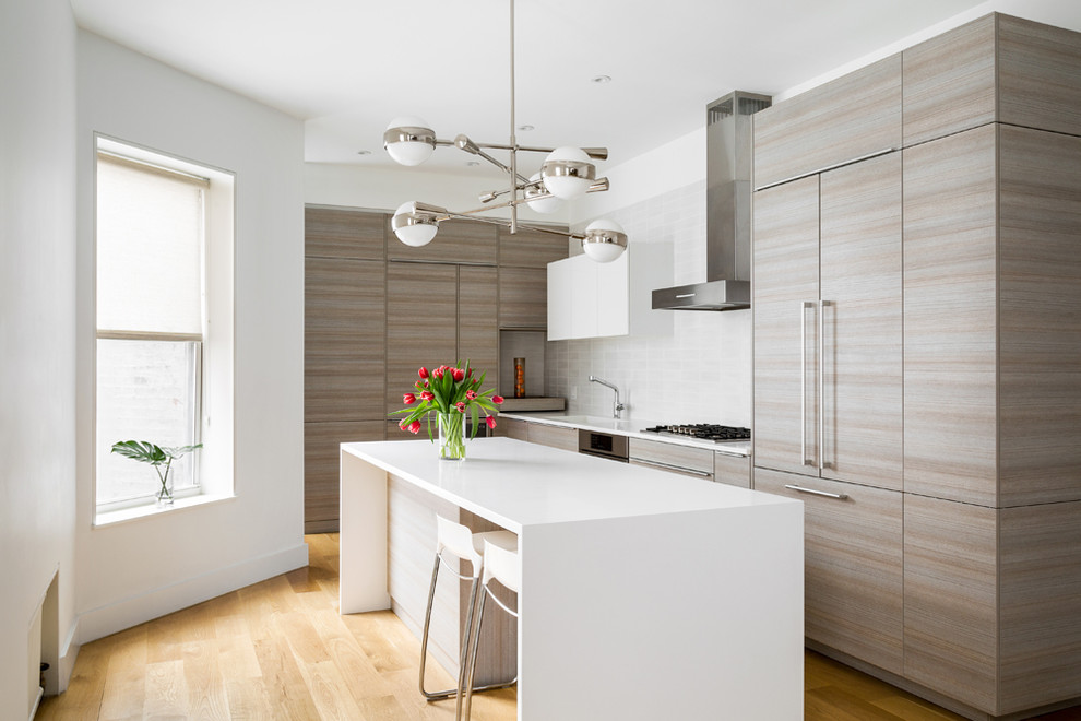 Design ideas for a contemporary kitchen in New York with an integrated sink, flat-panel cabinets, grey cabinets, grey splashback, panelled appliances, medium hardwood floors and with island.