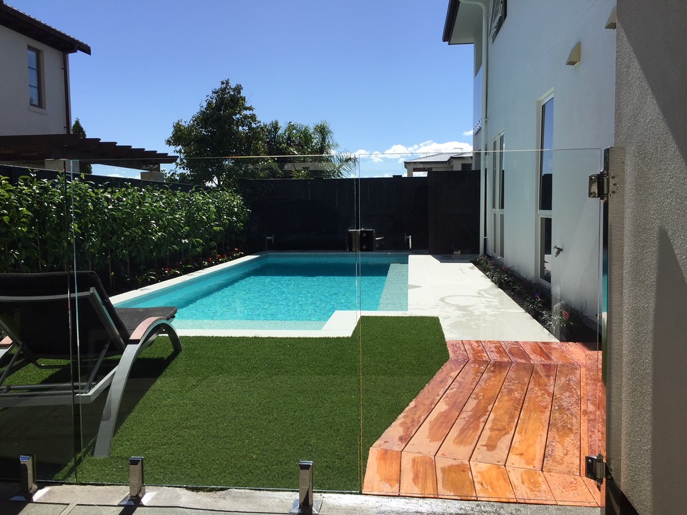 Photo of a small modern backyard custom-shaped natural pool in Auckland with natural stone pavers.
