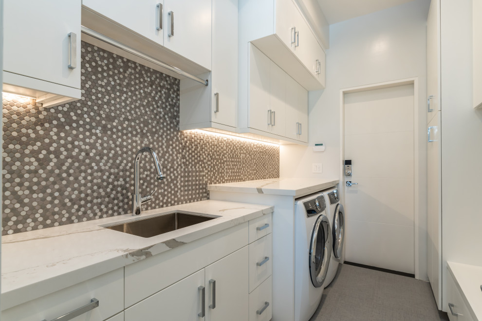 This is an example of a large modern single-wall utility room in San Francisco with an undermount sink, flat-panel cabinets, white cabinets, quartz benchtops, grey walls, porcelain floors, a side-by-side washer and dryer, grey floor and white benchtop.