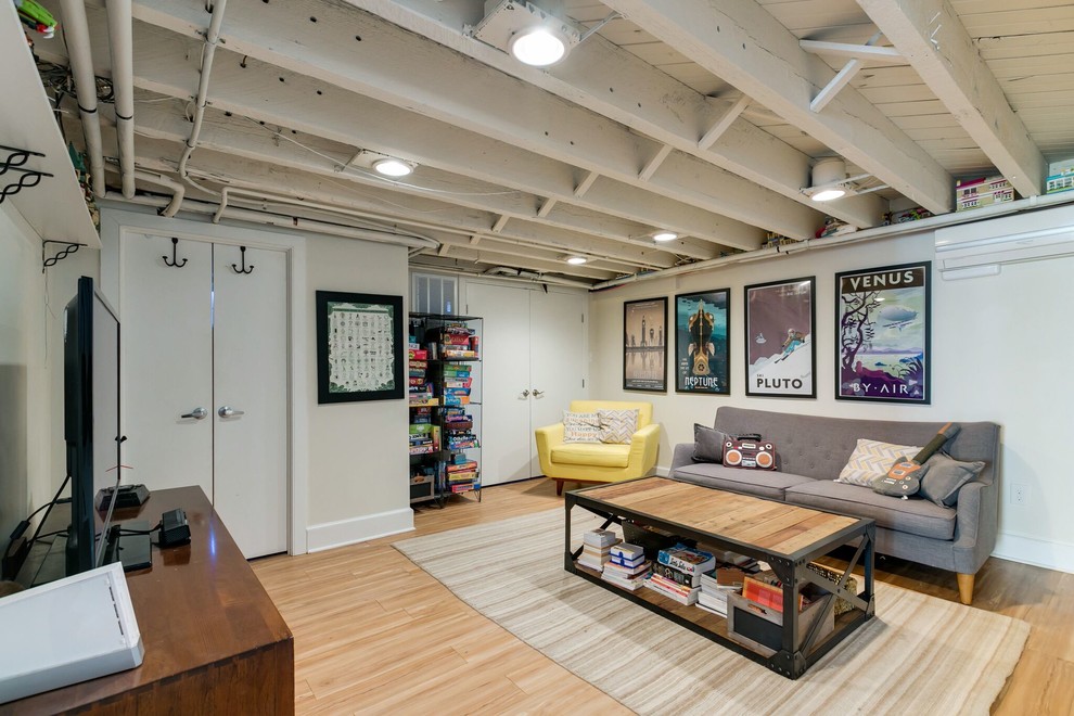 Industrial living room in Philadelphia with beige walls, light hardwood floors and a freestanding tv.
