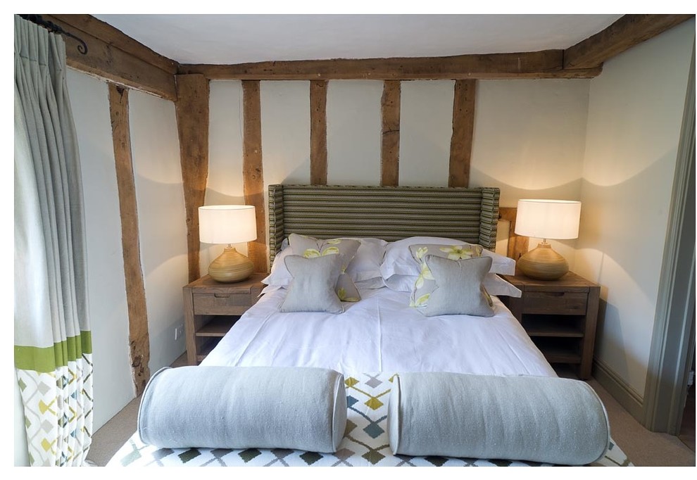 This is an example of a mid-sized country guest bedroom in Hampshire with beige walls and carpet.