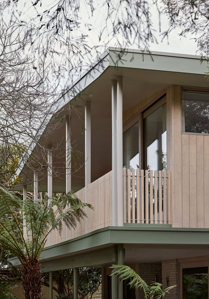 Design ideas for a mid-sized beach style two-storey brick beige house exterior in Melbourne with a gable roof and board and batten siding.