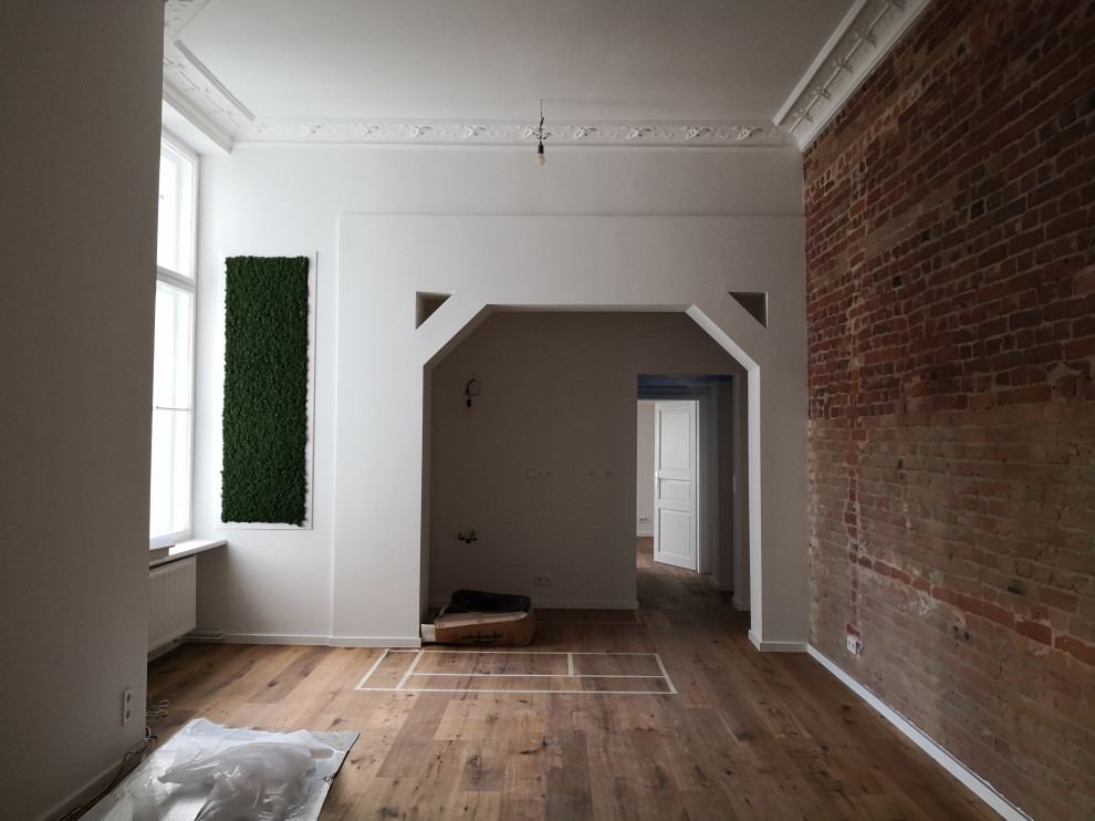 Mittelgroßes, Offenes Klassisches Wohnzimmer ohne Kamin mit weißer Wandfarbe, braunem Holzboden, braunem Boden und Ziegelwänden in Berlin