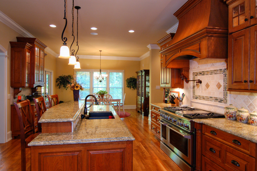 Mid-sized transitional single-wall medium tone wood floor and brown floor eat-in kitchen photo in Raleigh with an undermount sink, raised-panel cabinets, medium tone wood cabinets, granite countertops, beige backsplash, ceramic backsplash, stainless steel appliances, an island and brown countertops