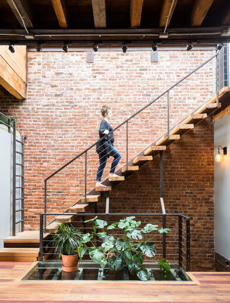 Inspiration for an industrial wood floating staircase in New York with open risers and cable railing.