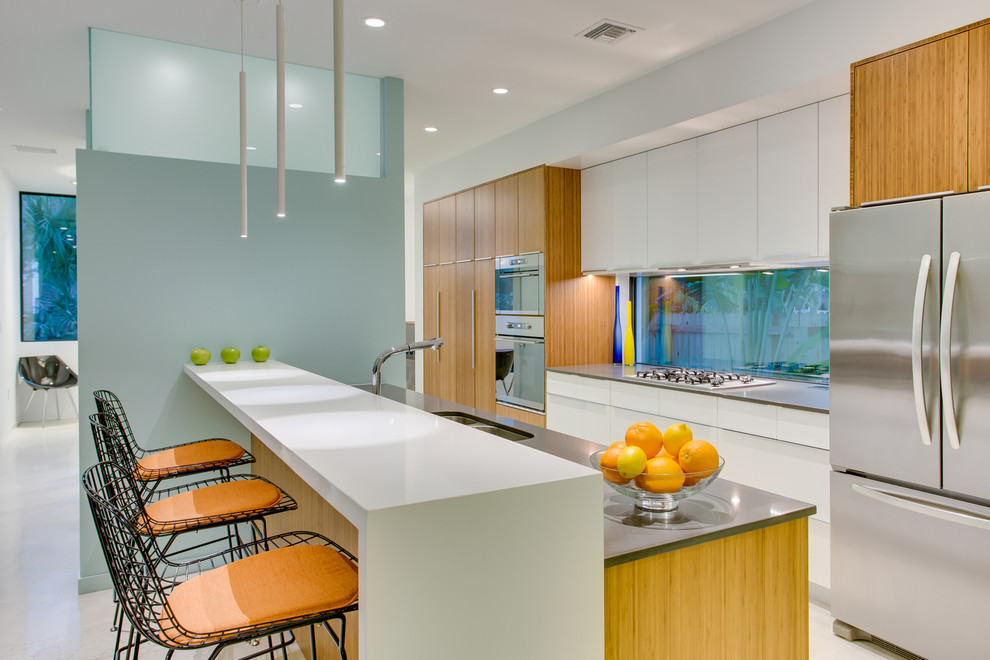 Kitchen - contemporary galley kitchen idea in Tampa with a double-bowl sink, flat-panel cabinets, medium tone wood cabinets, stainless steel appliances and an island