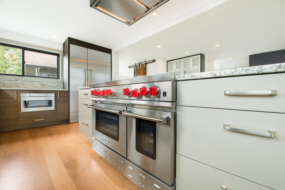 Open concept kitchen - large transitional u-shaped light wood floor and beige floor open concept kitchen idea in Seattle with an undermount sink, flat-panel cabinets, dark wood cabinets, granite countertops, gray backsplash, matchstick tile backsplash, stainless steel appliances, an island and multicolored countertops