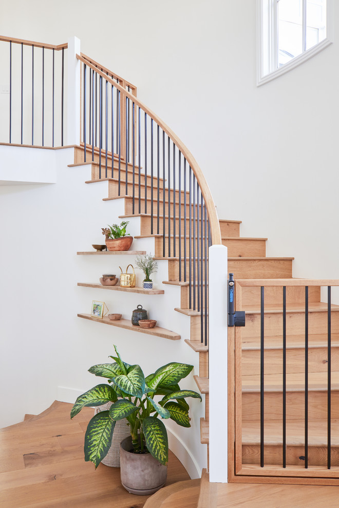 Design ideas for a beach style wood curved staircase in Los Angeles with wood risers and mixed railing.