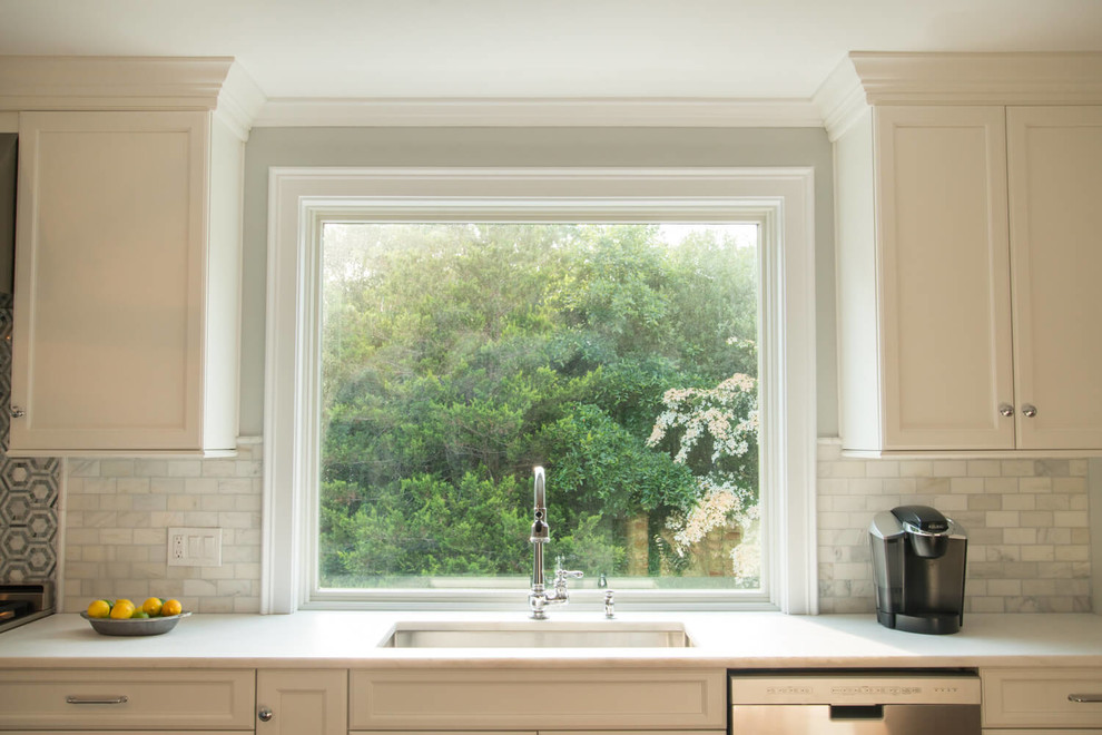 Inspiration for a transitional l-shaped kitchen remodel in Providence with a single-bowl sink, marble countertops, subway tile backsplash, stainless steel appliances and an island