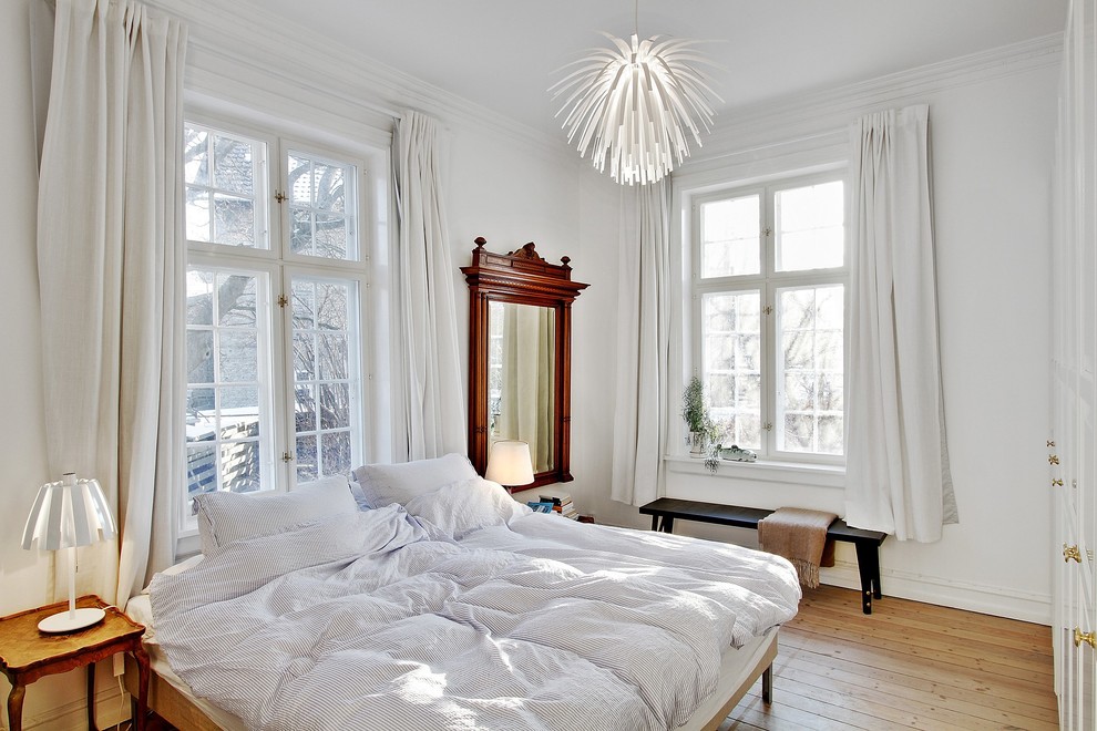 Photo of a large contemporary master bedroom in Copenhagen with white walls and medium hardwood floors.