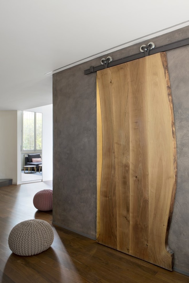 This is an example of a small contemporary foyer in Turin with grey walls, medium hardwood floors and brown floor.