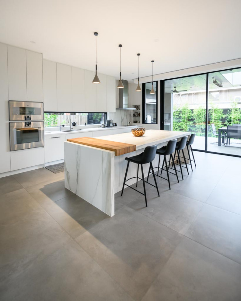 Inspiration for an expansive modern open plan kitchen in Melbourne with an undermount sink, flat-panel cabinets, white cabinets, multi-coloured splashback, stainless steel appliances, porcelain floors, with island, grey floor and multi-coloured benchtop.