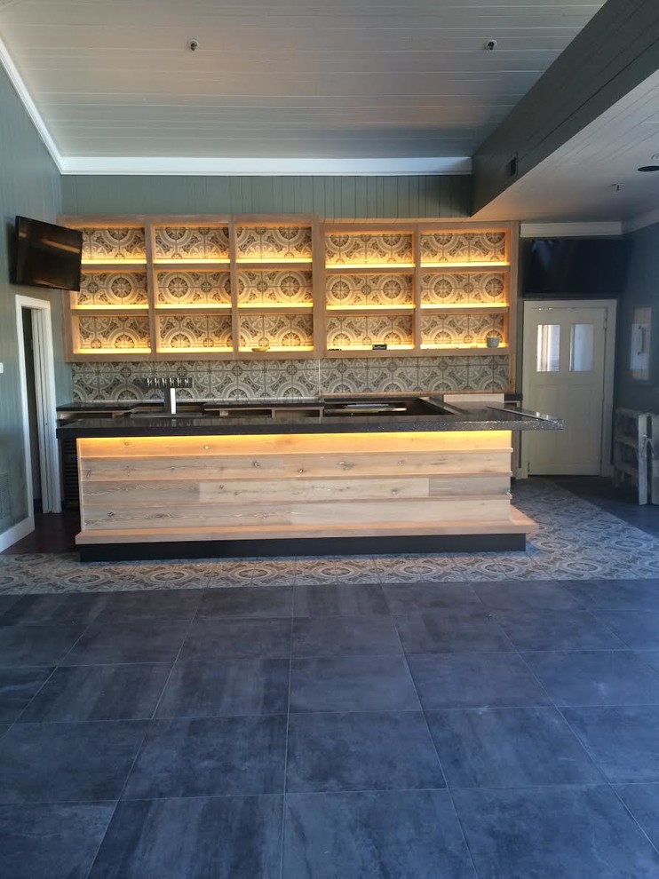 This is an example of a large contemporary l-shaped seated home bar in Sacramento with open cabinets, light wood cabinets, multi-coloured splashback, mosaic tile splashback, ceramic floors, grey floor, granite benchtops and black benchtop.