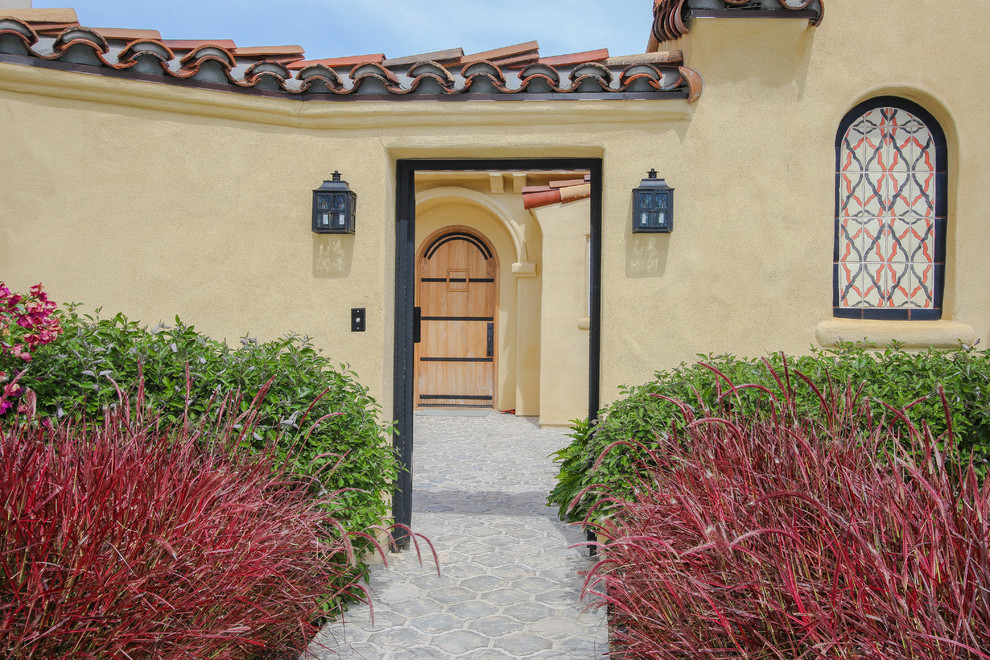 Design ideas for a mediterranean entryway in San Diego with yellow walls, a single front door and a light wood front door.