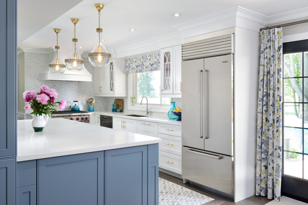 Large transitional l-shaped eat-in kitchen in Toronto with an undermount sink, shaker cabinets, blue cabinets, quartz benchtops, white splashback, marble splashback, stainless steel appliances, medium hardwood floors, with island and white benchtop.