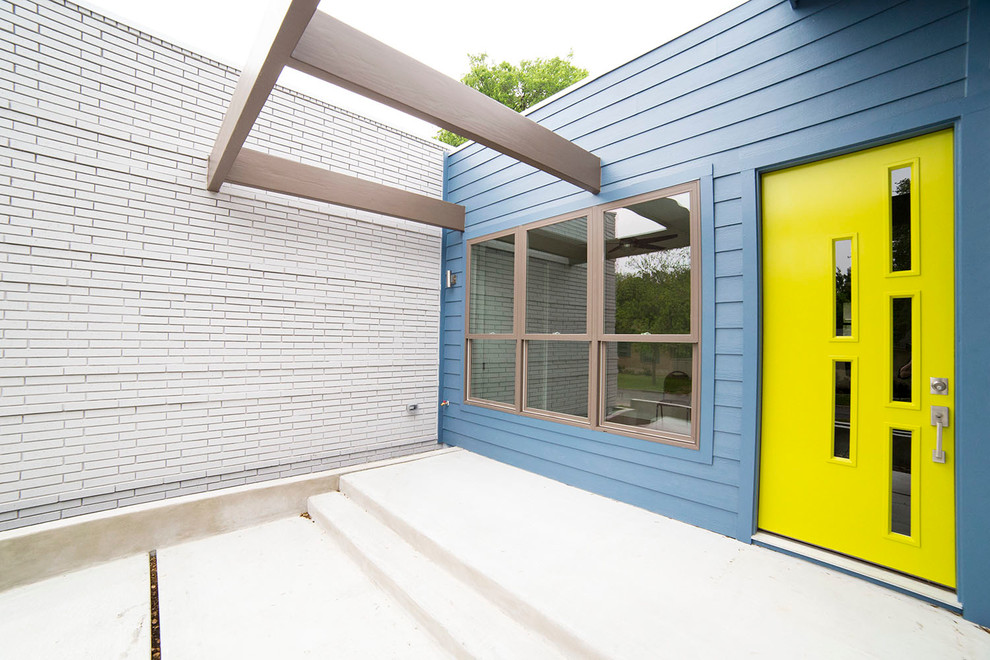 This is an example of a contemporary front door in Austin with a single front door, a yellow front door and blue walls.