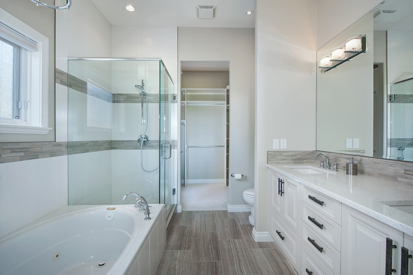 Drop-in bathtub - mid-sized transitional master porcelain tile drop-in bathtub idea in Calgary with raised-panel cabinets, white cabinets, a two-piece toilet, beige walls, an undermount sink and quartz countertops
